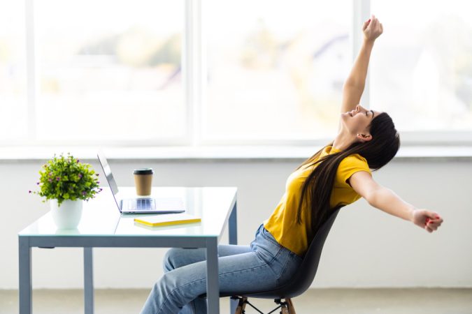 mujer-negocios-relajandose-manos-detras-cabeza-sentada-silla-oficina